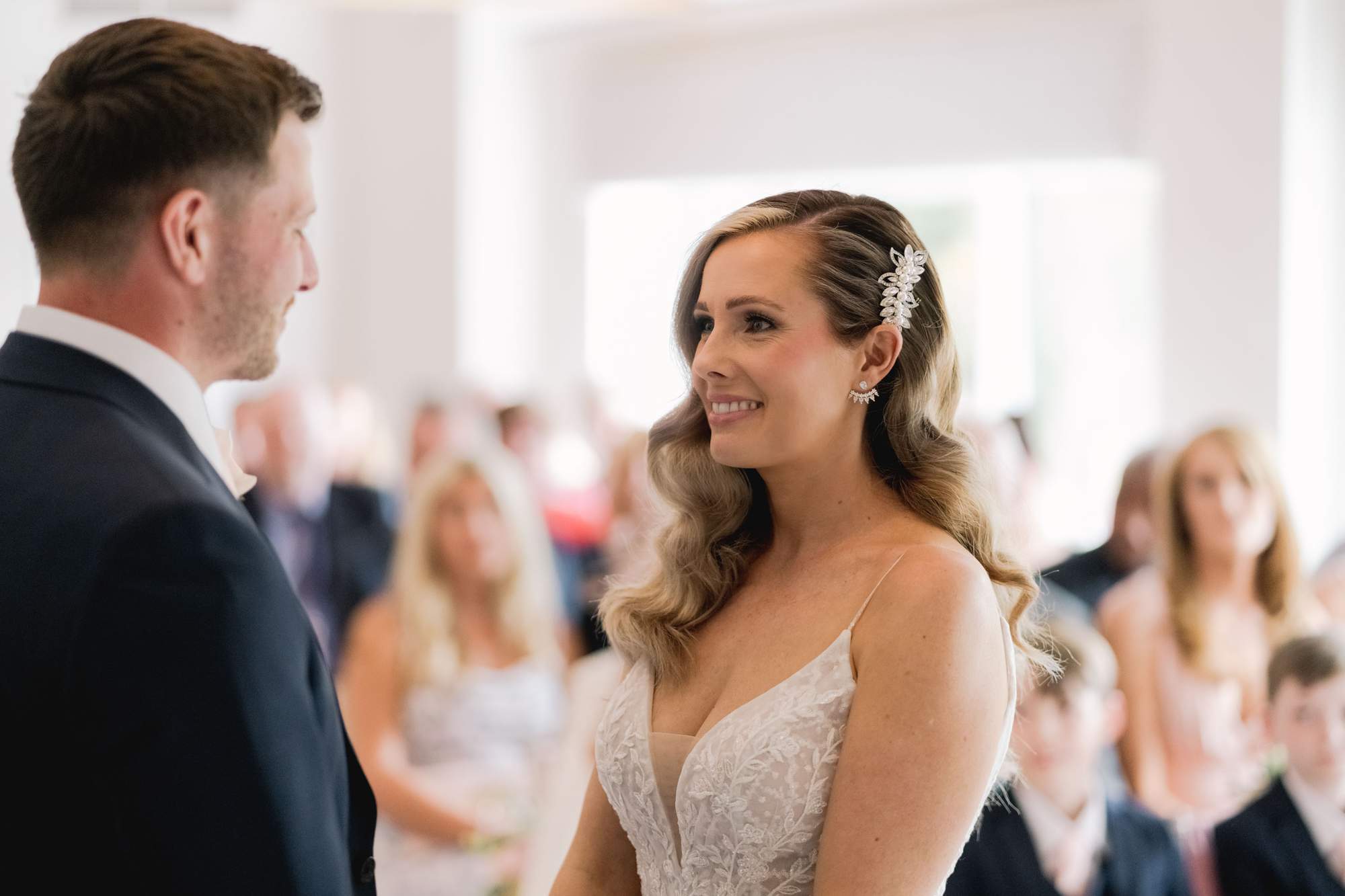 Bride and groom smiling at each other during their wedding ceremony at Cottesmore Golf Club in Sussex.