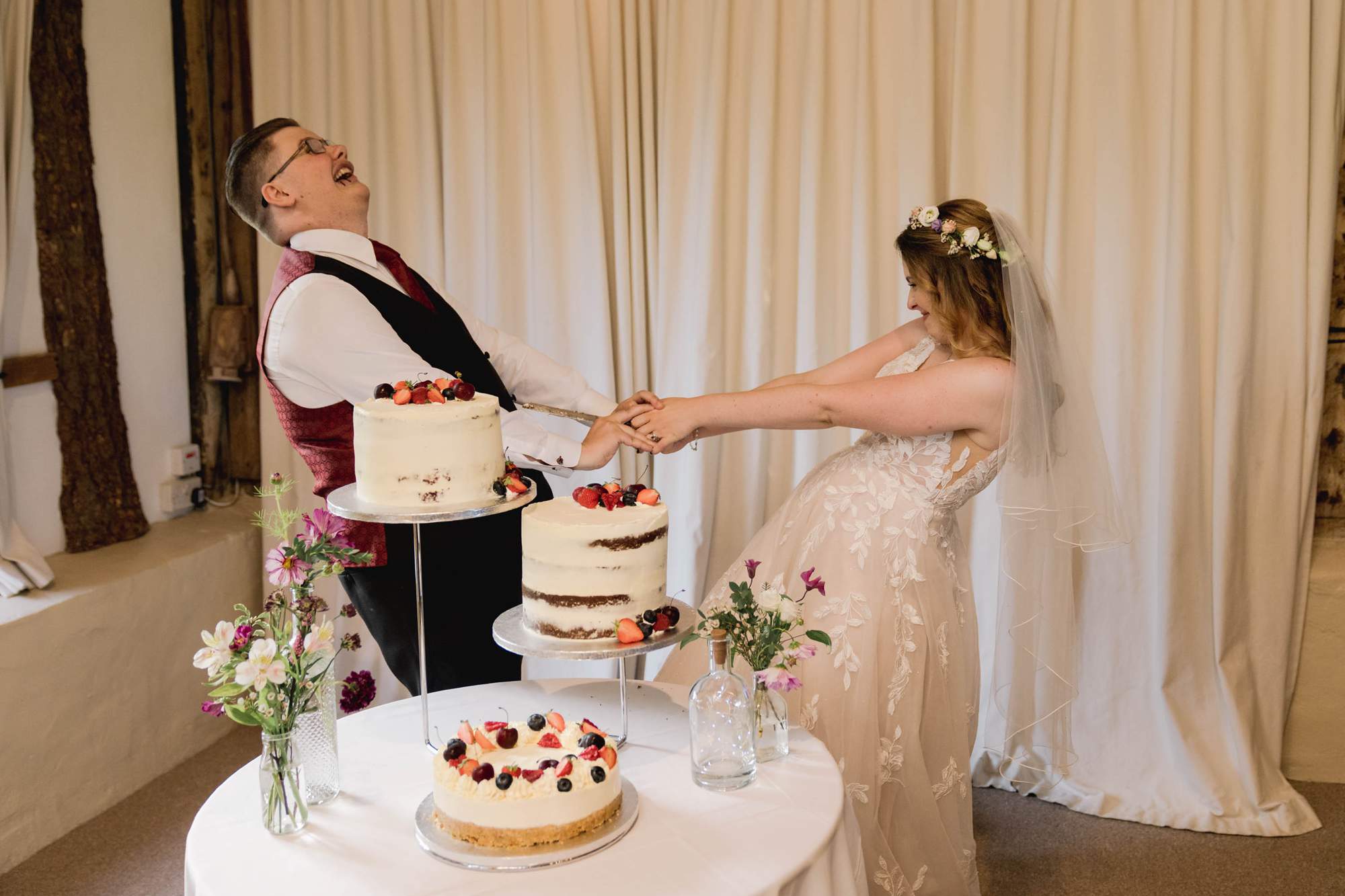 Bride and groom cut the cake on their wedding day at the Clock Barn in Hampshire.