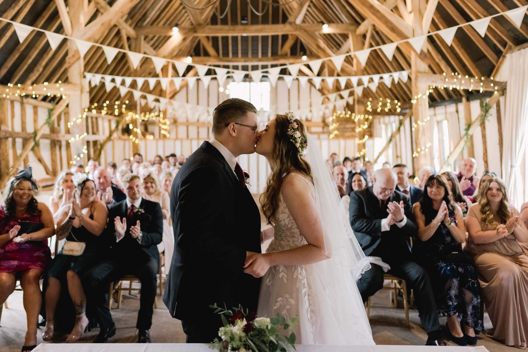 Bride and groomkiss during the ceremony on their wedding day at the Clock Barn venue in Hampshire.