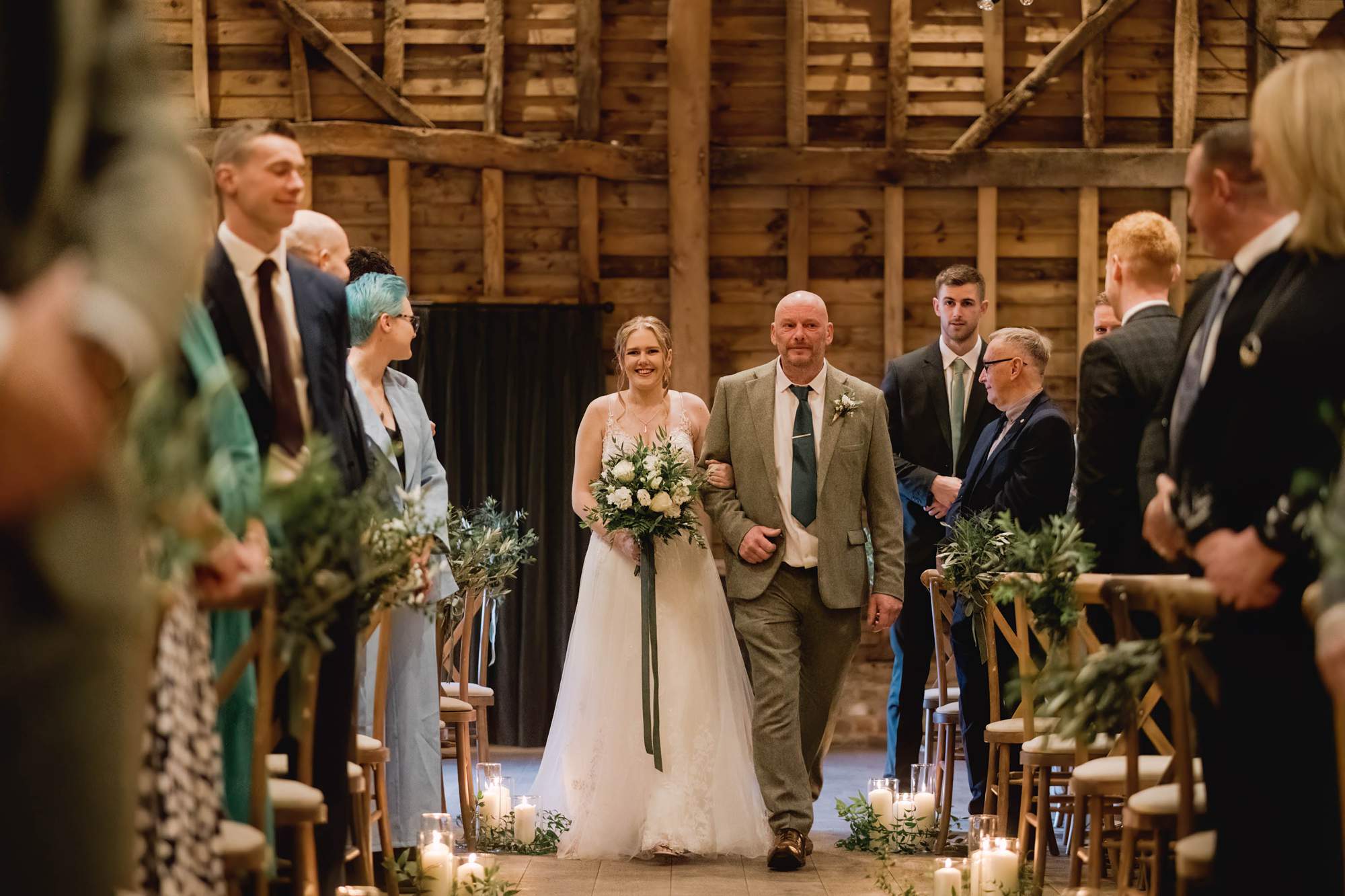 Bride walking down the aisle in the barn with her father.