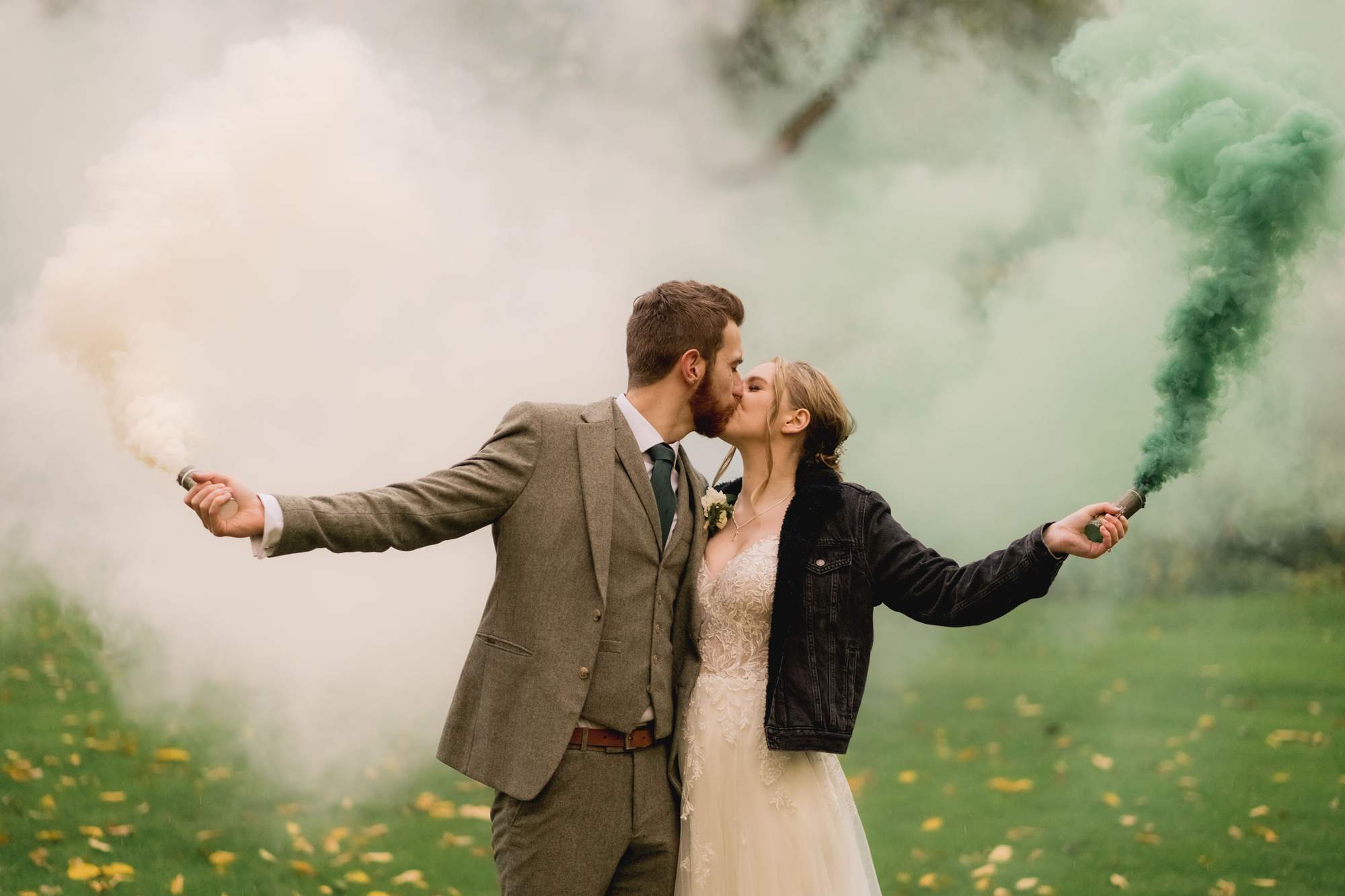 Bride and groom kiss as they hold smoke bombs at The Farmhouse at Redcoats in Hitchin.