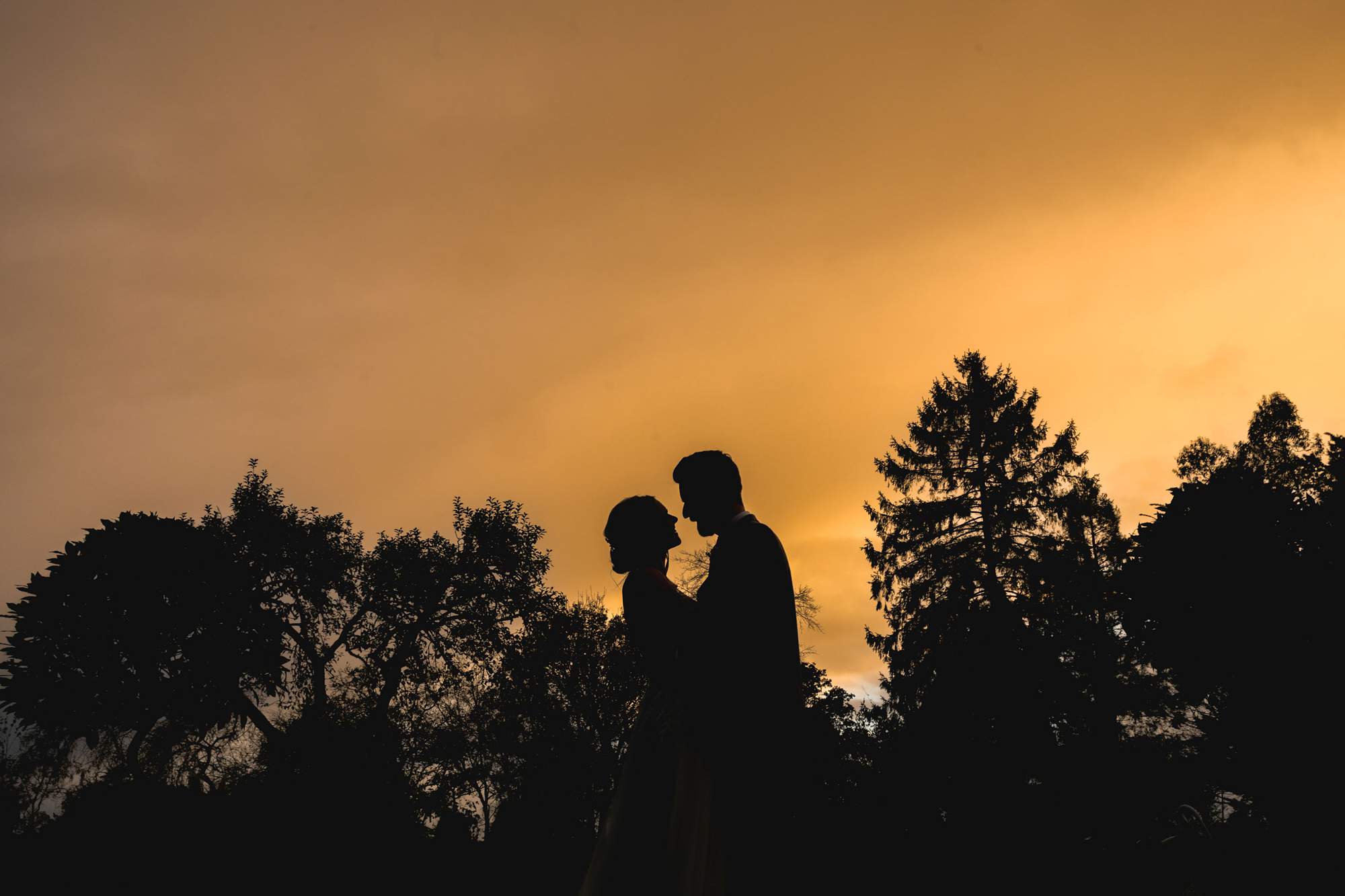 Bride and groom silhouetted at sunset at The Farmhouse at Redcoats in Hitchin.