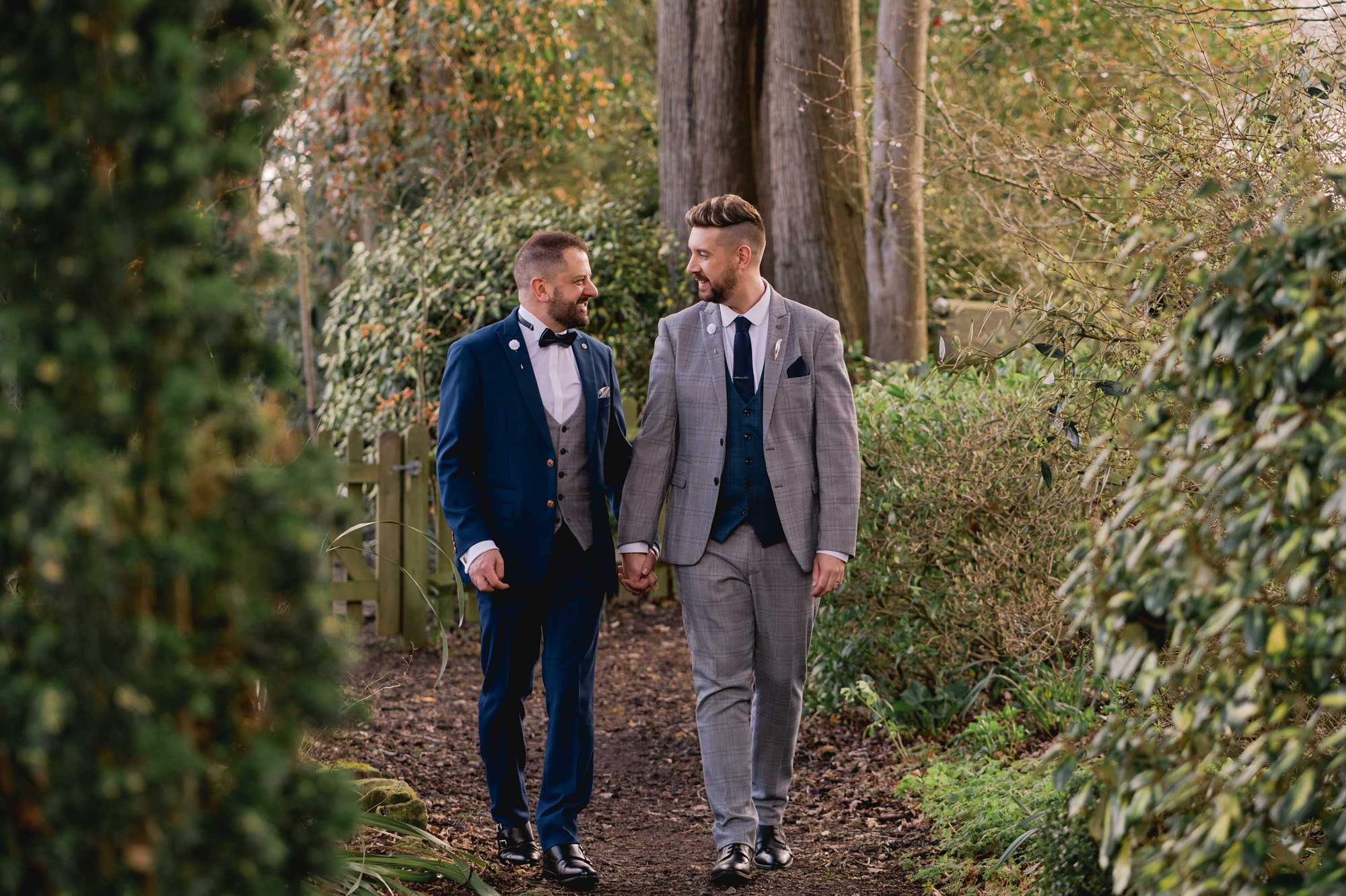 Two grooms smiling whilst they take a stroll on their wedding day at Wickwoods Country Club in East Sussex.