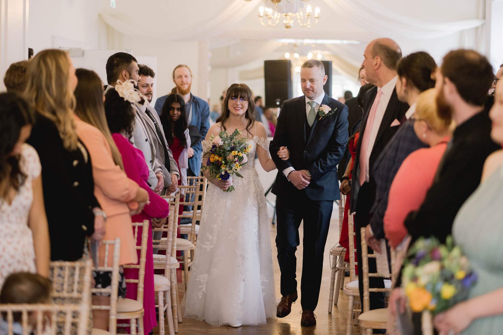 bride walks down the aisle on her wedding day at Pelham House in East Sussex.