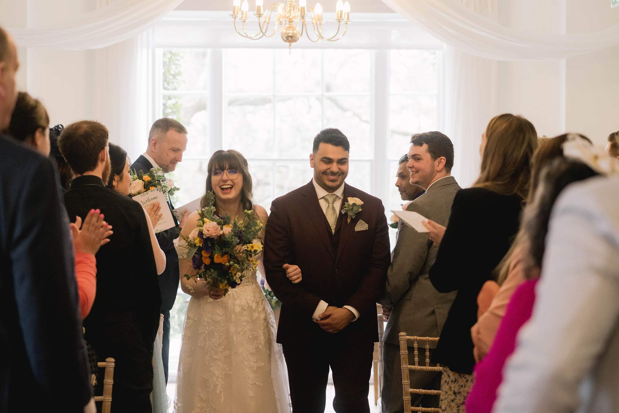 Bride and groom smiling whilst they take a stroll down the aisle on their wedding day at Pelham House in East Sussex.
