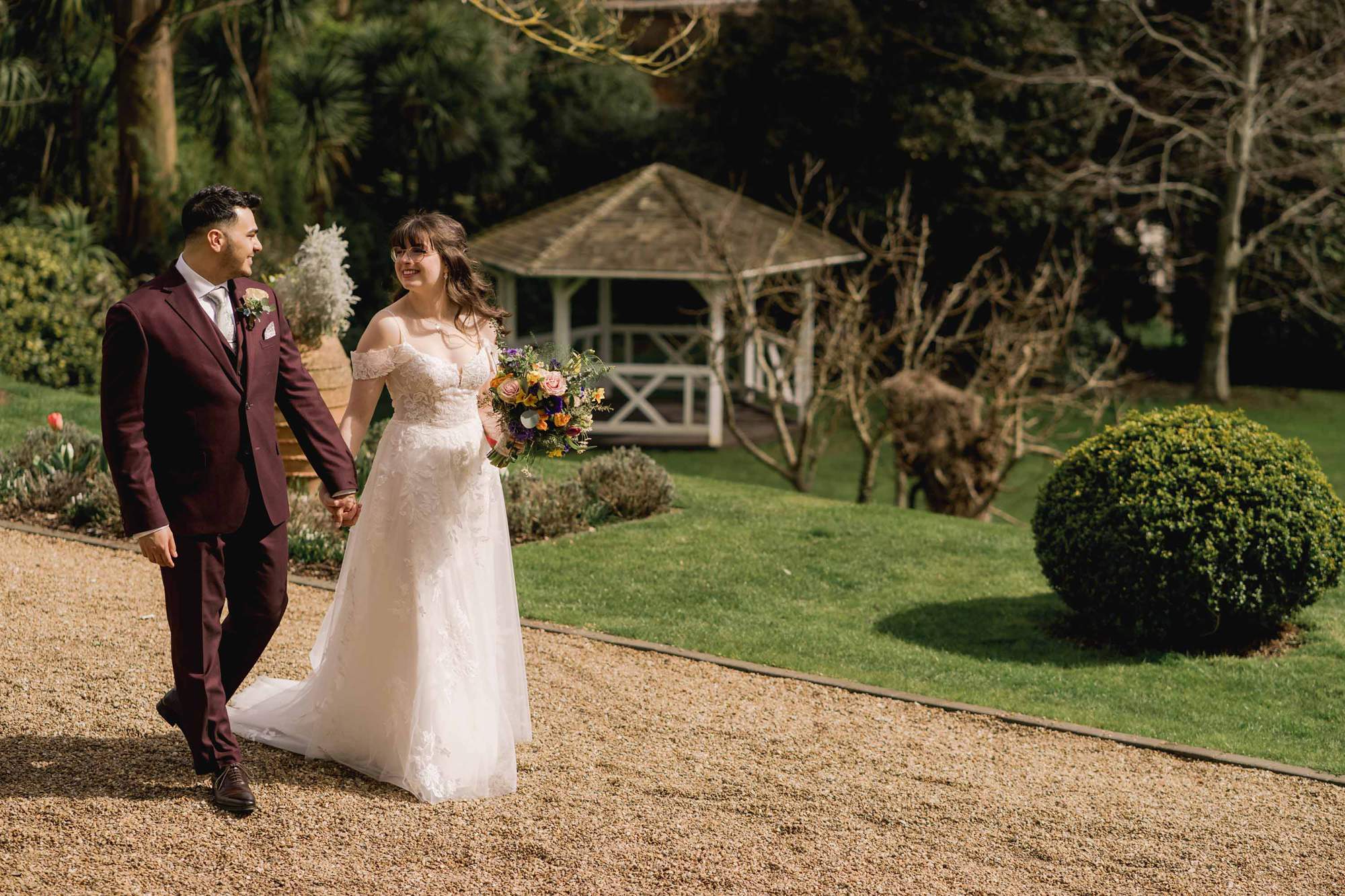 Bride and groom smiling whilst they take a stroll on their wedding day at Pelham House in East Sussex.