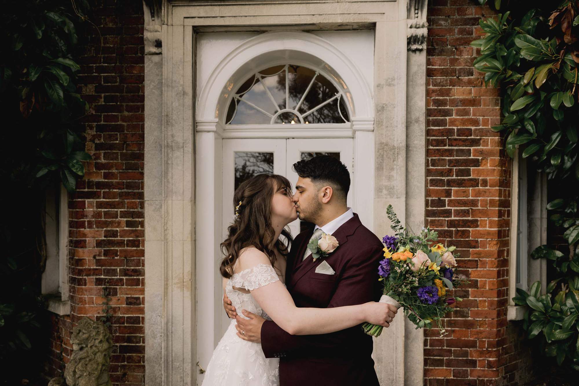 Bride and groom kiss on their wedding day in the doorway of Pelham House in East Sussex.