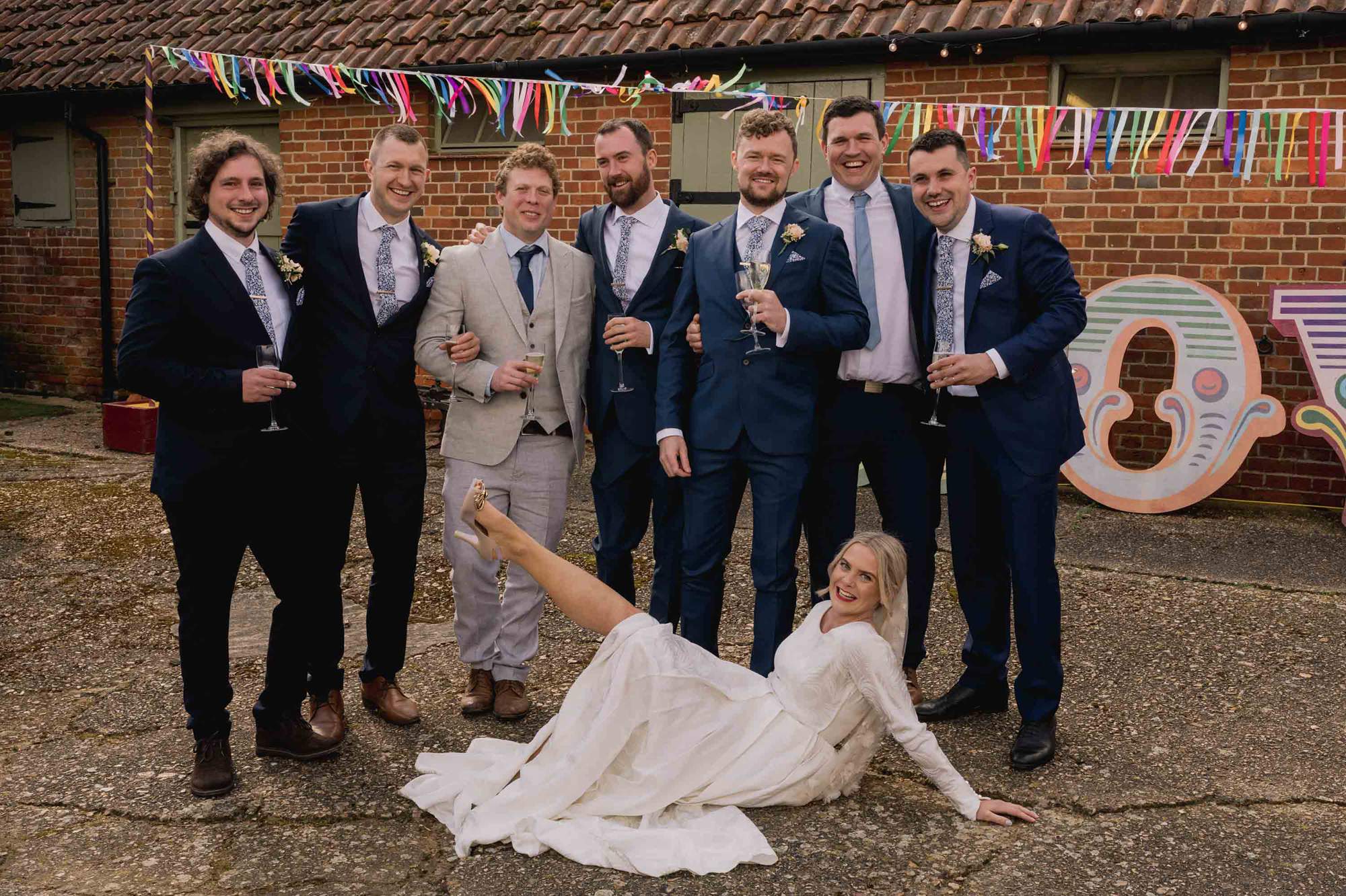 Bride pulls an elaborate pose with the groomsmen at a wedding Myrtles Courtyard in Surrey.