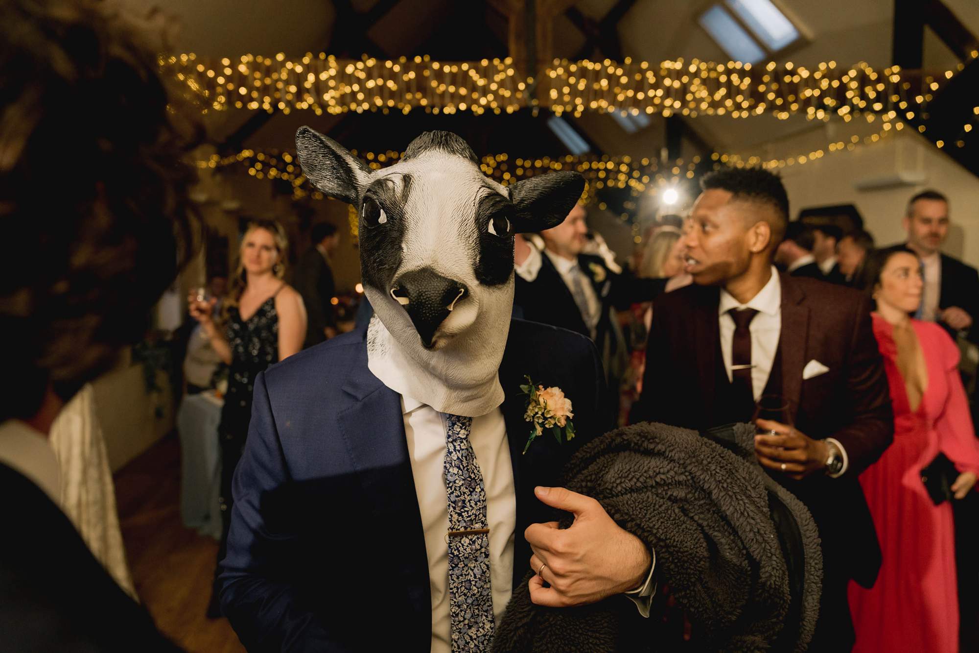 A guest dancing on the dance floor dressed as a cow at a wedding in Surrey.
