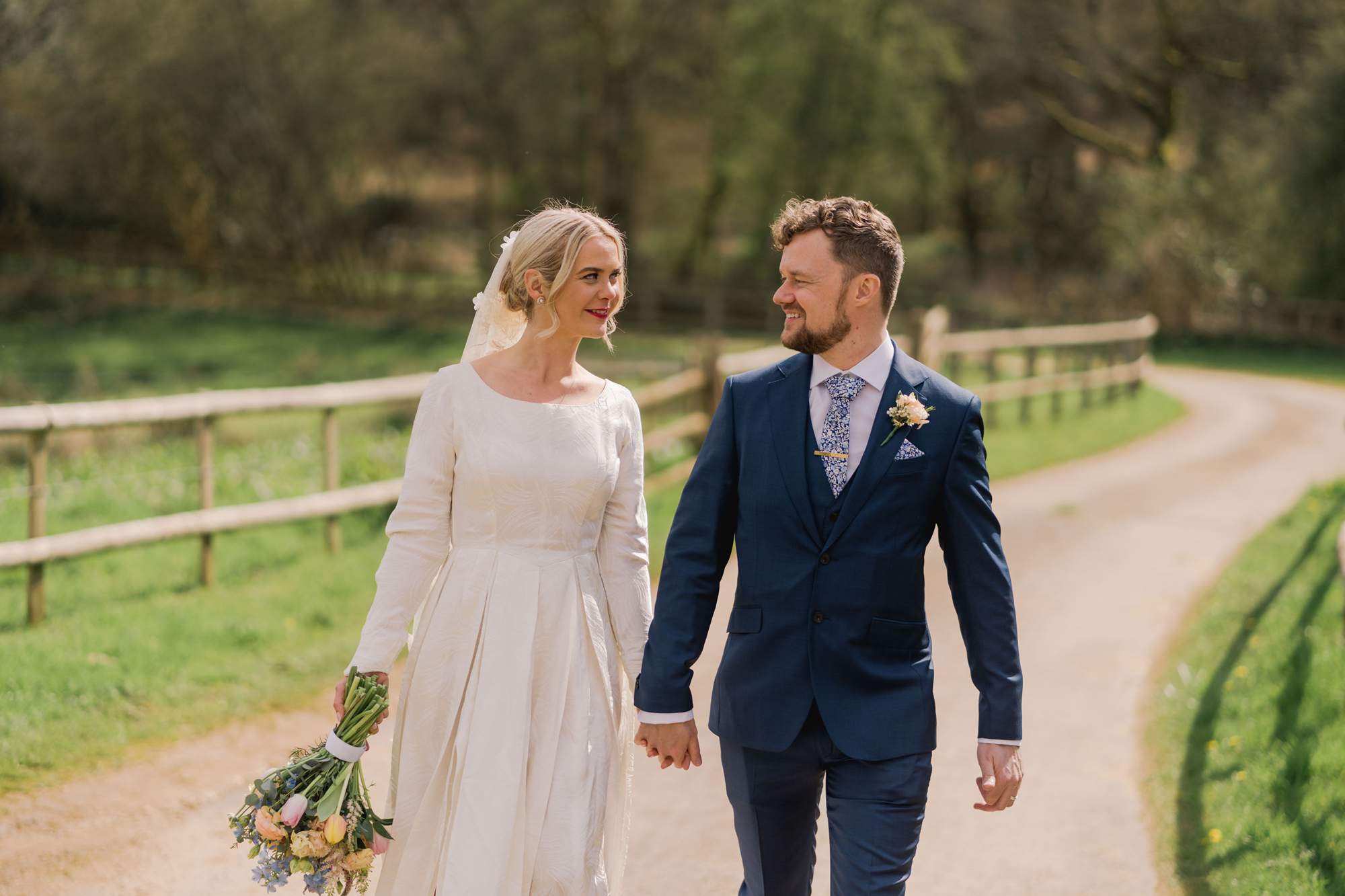 Bride and groom smiling whilst they take a stroll on their wedding day.