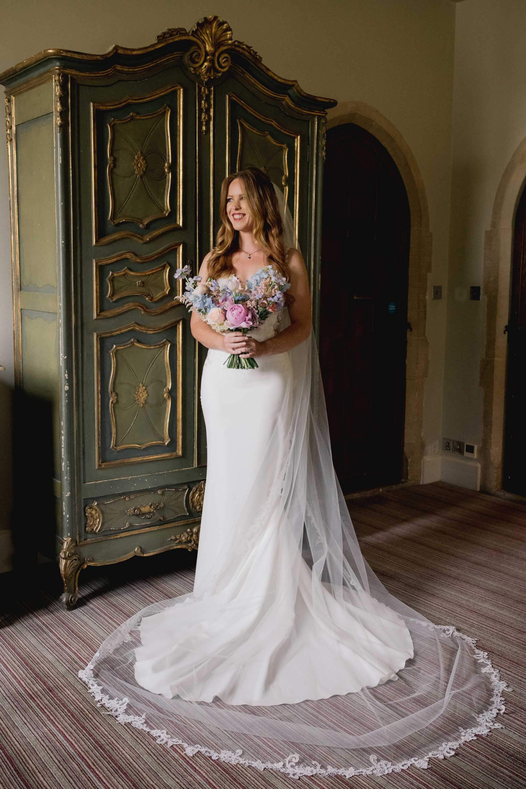 A bride in a beautiful wedding dress holding her bouquet of flowers at Amberley Castle in West Sussex.