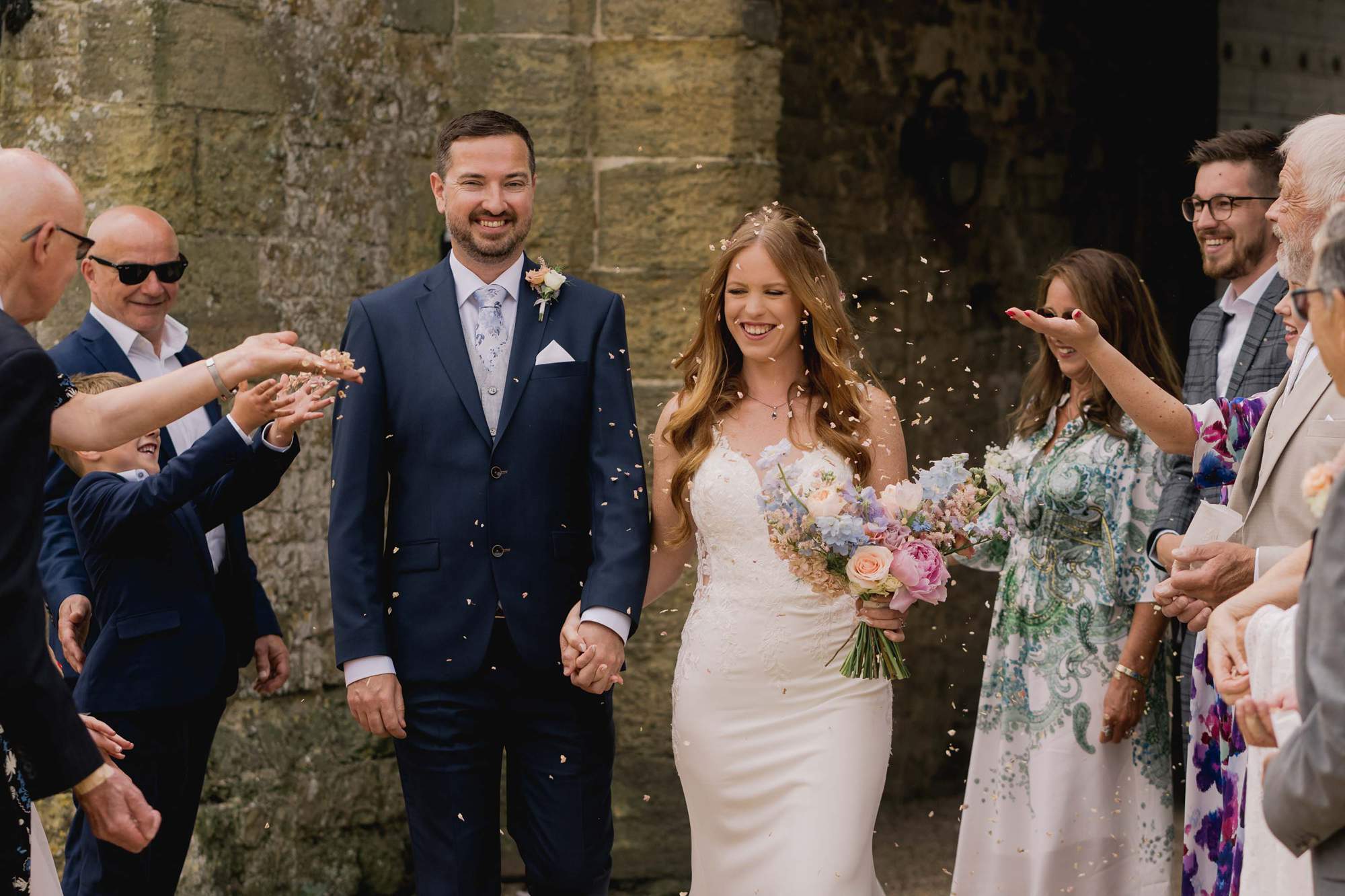 Wedding guests throw confetti at the bride and groom on their wedding day at Amberley Castle in West Sussex.
