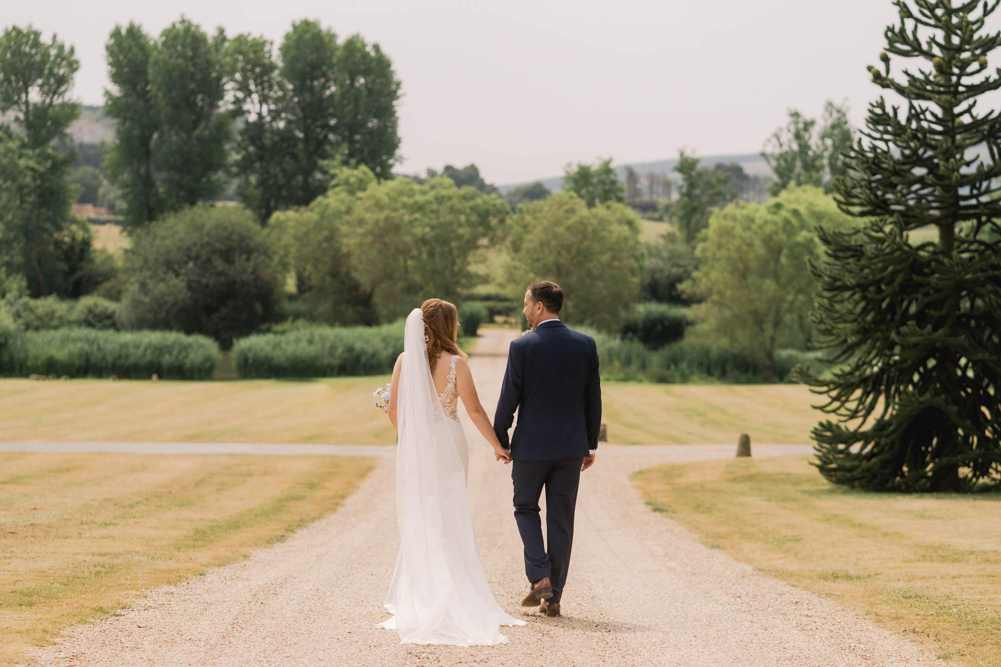 Bride and groom smiling whilst they take a stroll on their wedding day at Amberley Castle in West Sussex.