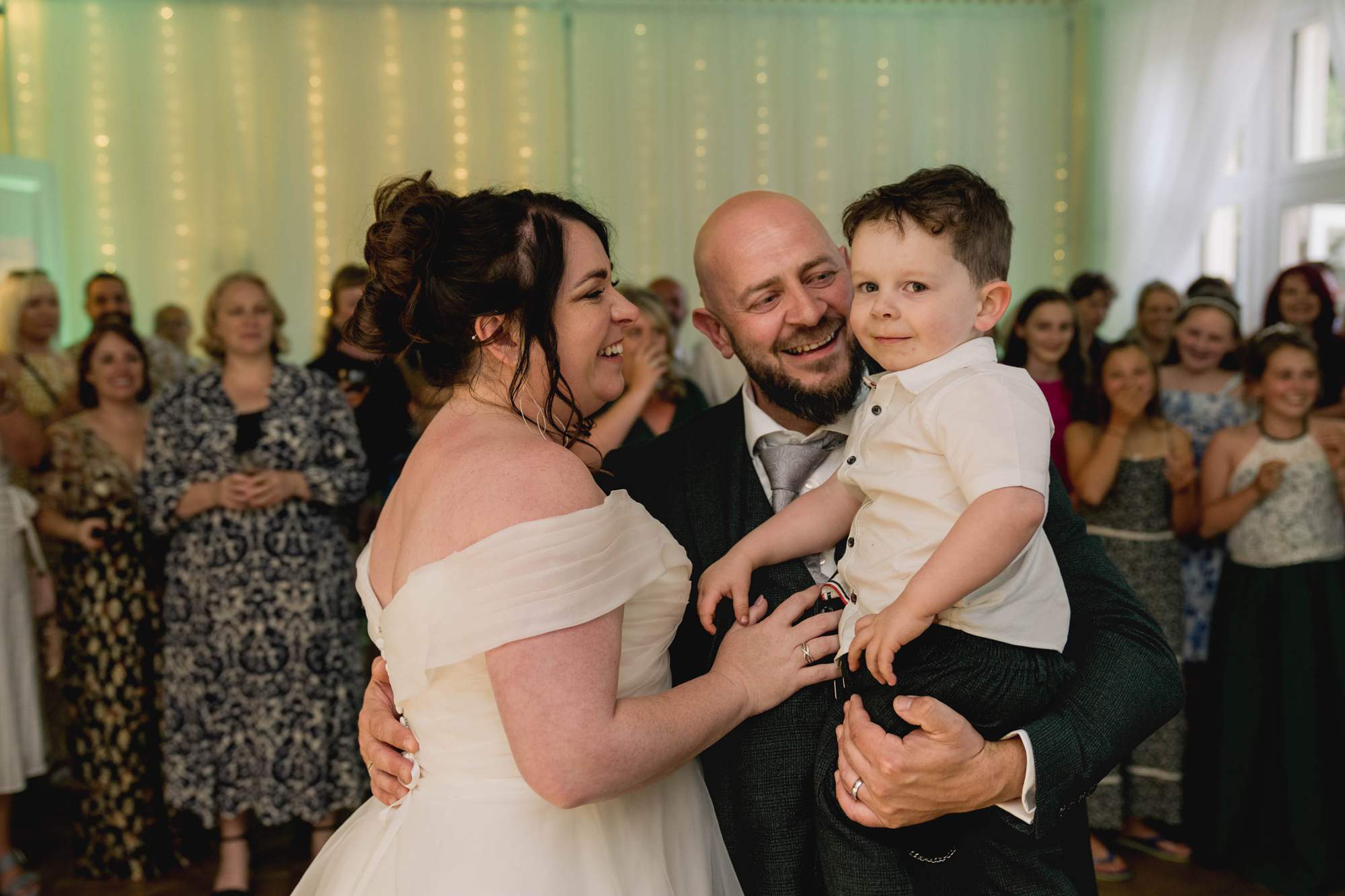 Bride and groom smile at their toddler son during their first dance at Highley Manor in Sussex.