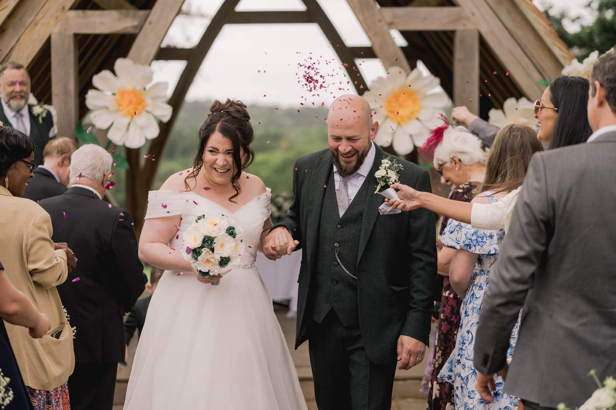 Outdoor ceremony with bride and groom running through the confetti line at Highley Manor wedding venue in Sussex.