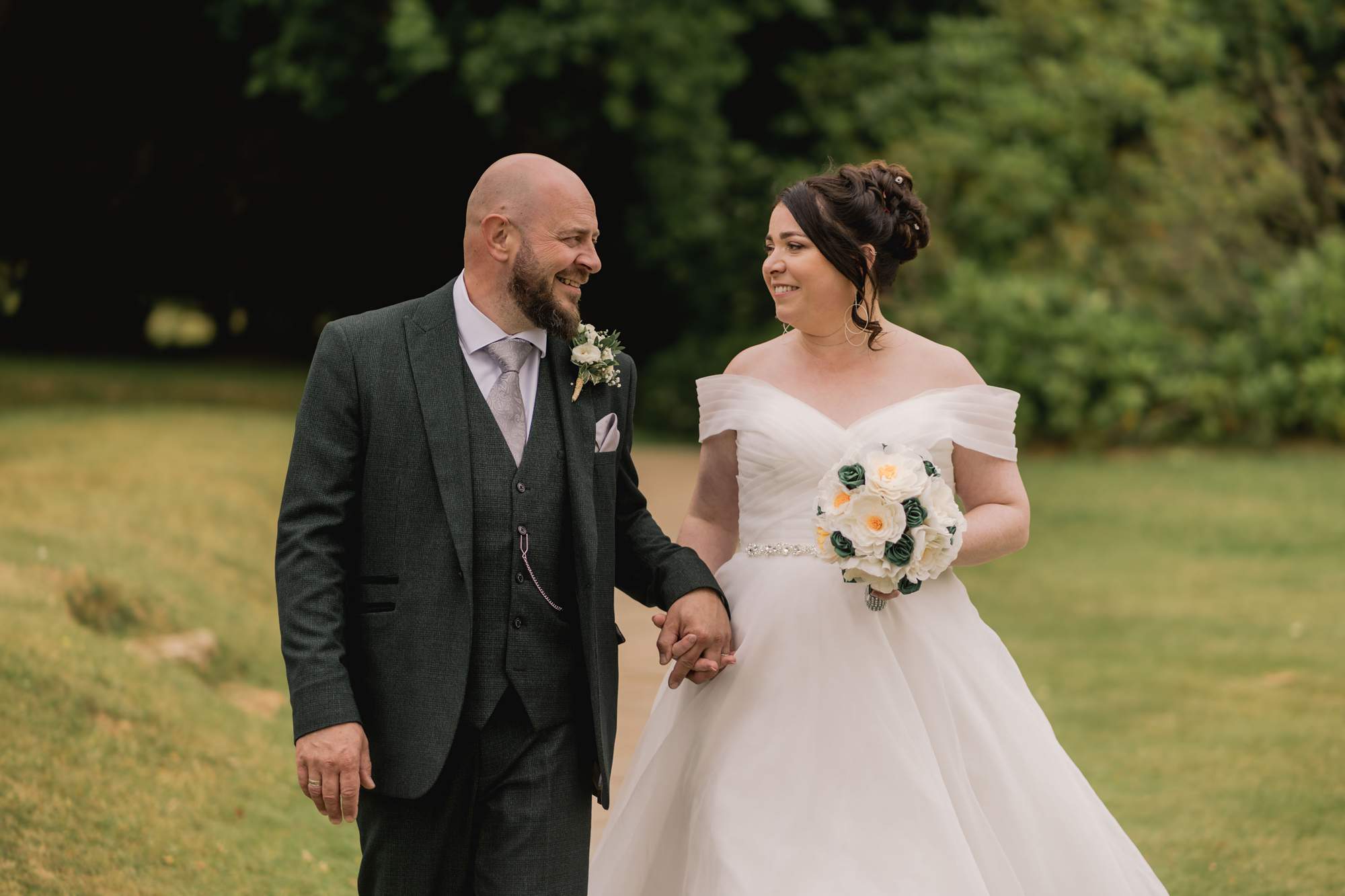 Bride and groom smiling at each other as they take a stroll at Highley Manor.