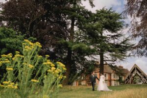Bride and groom walk in the sunshine at Highley Manor wedding venue in Sussex.