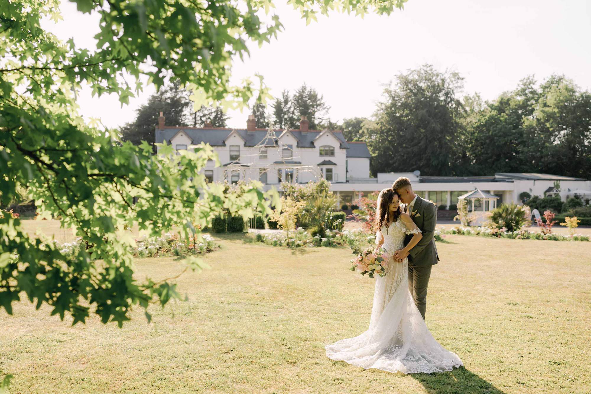 Bride and groom hug closely on their sunny wedding day at Southdowns Manor.
