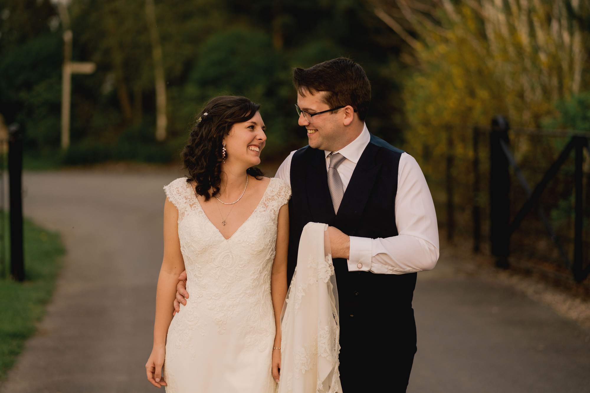 Bride and groom smiling whilst they take a stroll on their wedding day at Swallows Nest Barn in Warwickshire.
