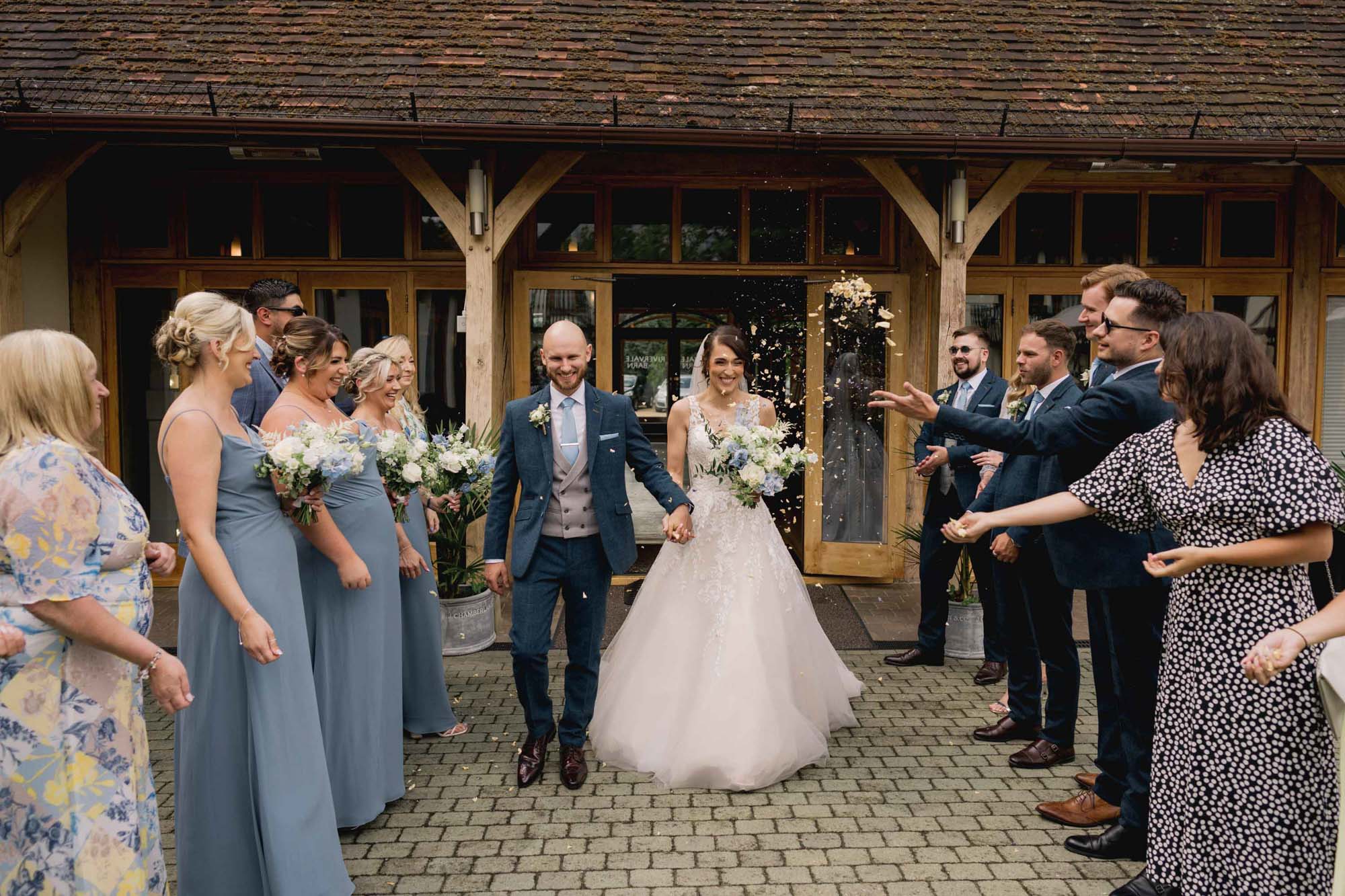 Wedding guests throw confetti at the bride and groom on their wedding day at Rivervale Barn in Hampshire.
