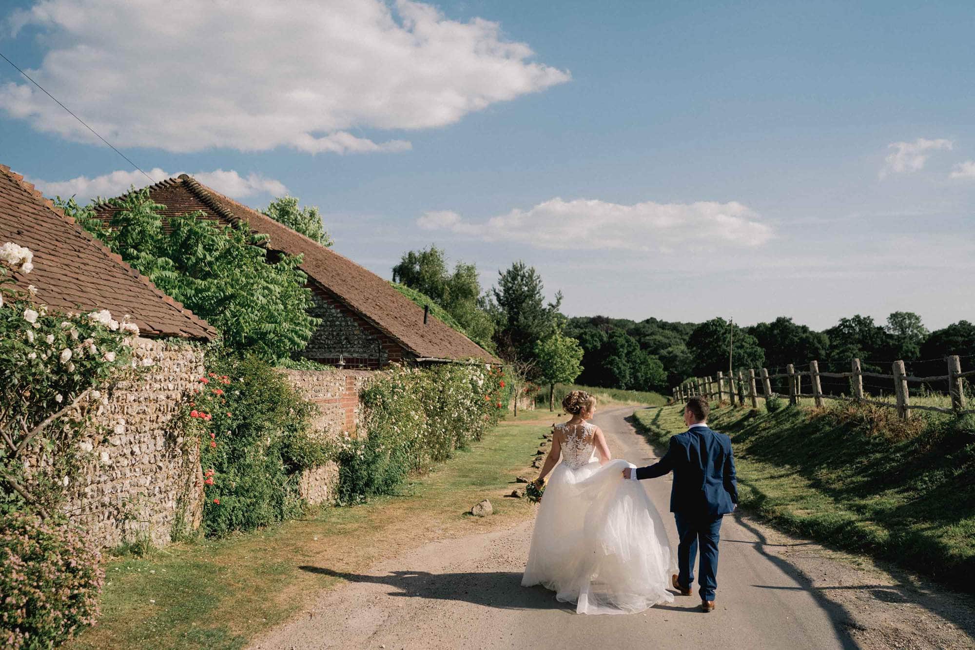 Bride and groom smiling whilst they take a stroll on their wedding day outside a barn in St. Albans.